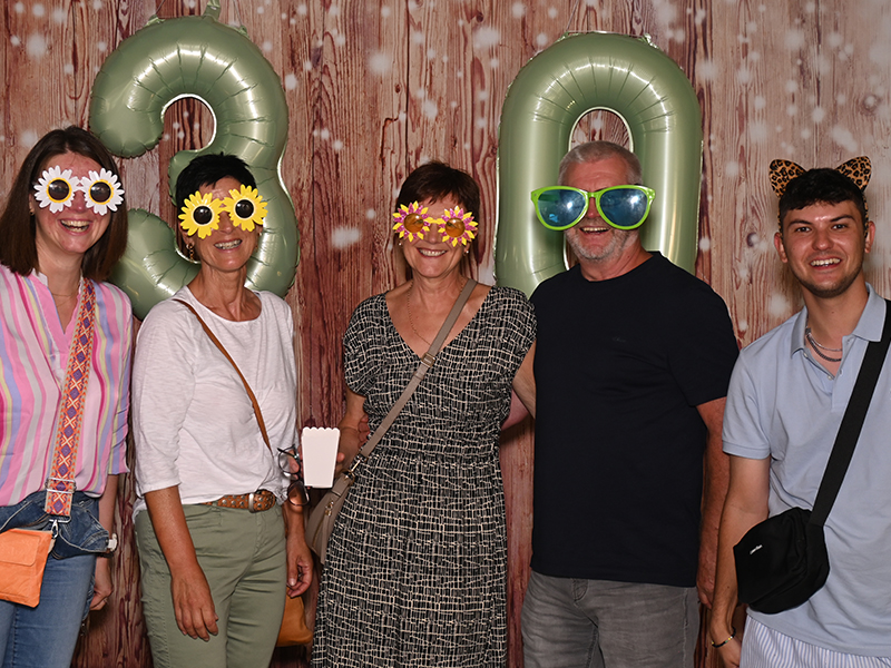 Three colleagues together in a photo booth at the company summer party