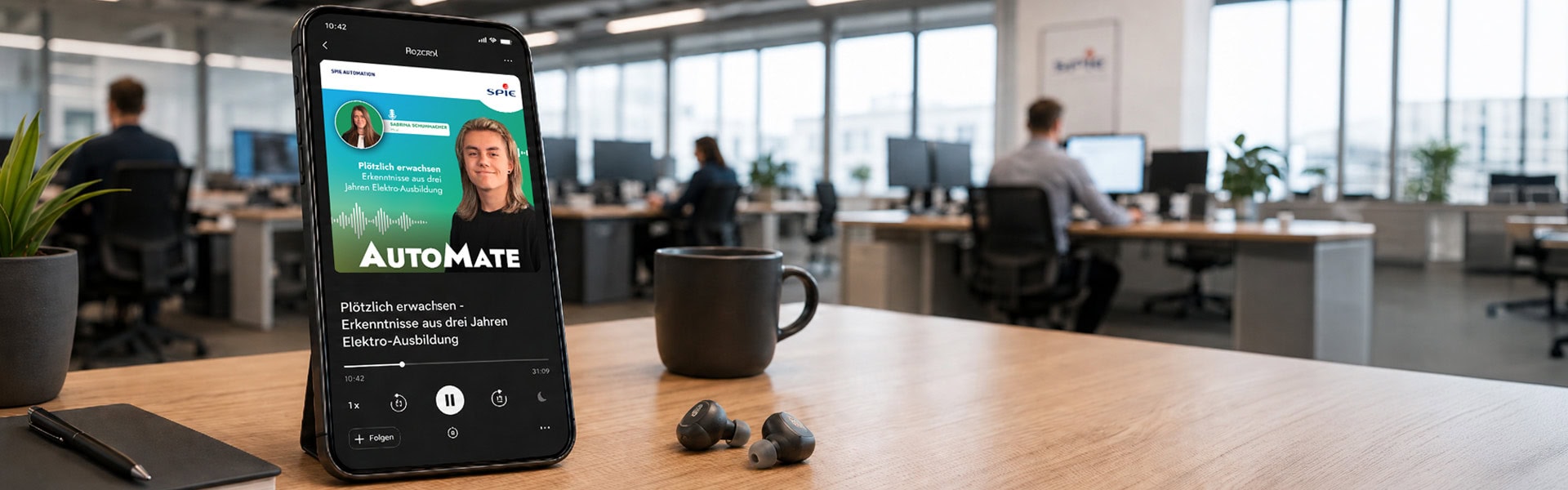 Smartphone mit geöffnetem Podcast-Player für den SPIE AutoMate Podcast und der Folge „Plötzlich erwachsen - Erkenntnisse aus drei Jahren Elektro-Ausbildung“ auf einem Schreibtisch im modernen Büro. Daneben liegen In-Ear-Kopfhörer, im Hintergrund sind unscharf Arbeitsplätze und Mitarbeitende zu sehen.